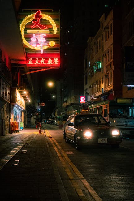 Neon-lit city street at night with headlights and storefront signs, illustrating ghosting and washed highlights.