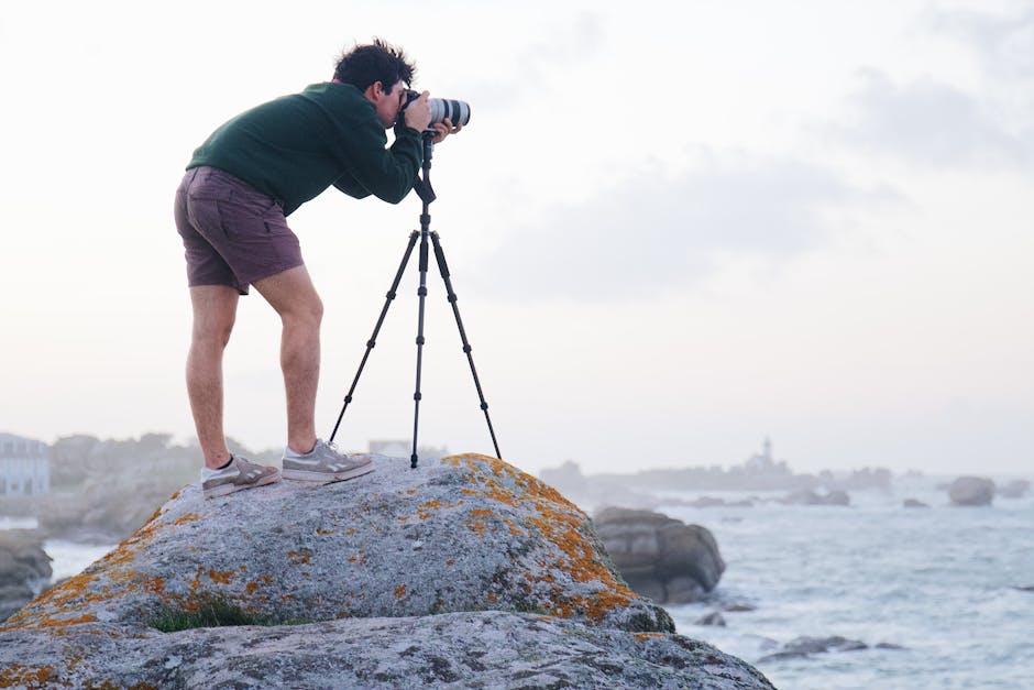 Tripod setup on a rocky shoreline with wind and ocean backdrop for stable landscape framing