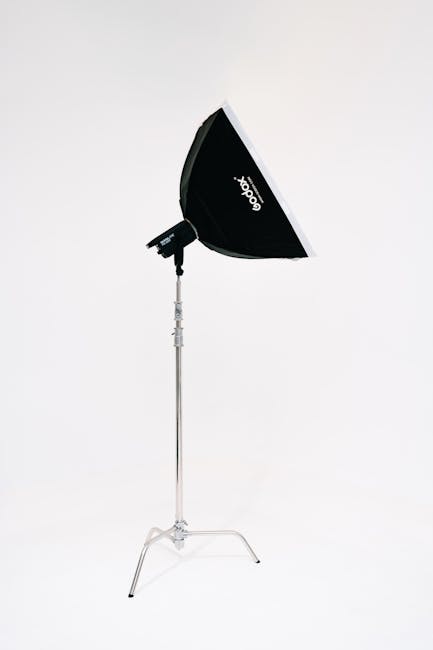 Photographer lighting a studio portrait with a softbox, showing crisp, controlled face light.